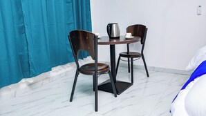Una pequeña mesa redonda de comedor con dos sillas, una cafetera y una taza sobre la mesa.