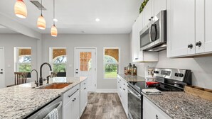 A kitchen with granite countertops, stainless steel appliances, and pendant lighting. - Peaceful 3-Bedroom Ranch Retreat Near Blanco (Blanco)