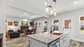 A modern kitchen with a granite countertop, white cabinetry, and a built-in dishwasher. - Peaceful 3-Bedroom Ranch Retreat Near Blanco (Blanco)