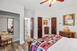 A bedroom with a bed, a chair, a dresser, a mirror, and a door leading to another room. - Peaceful 3-Bedroom Ranch Retreat Near Blanco (Blanco)