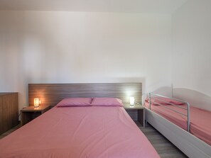 A bedroom with a single bed, a nightstand, a bedside table, and a wall-mounted light fixture.