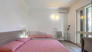 Una camera da letto con due letti, una sedia, una scrivania e una finestra.