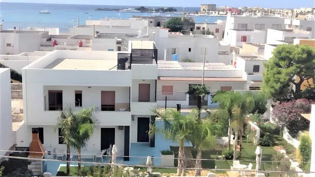 Un quartiere residenziale con architettura moderna, una piscina e vista sul mare.
