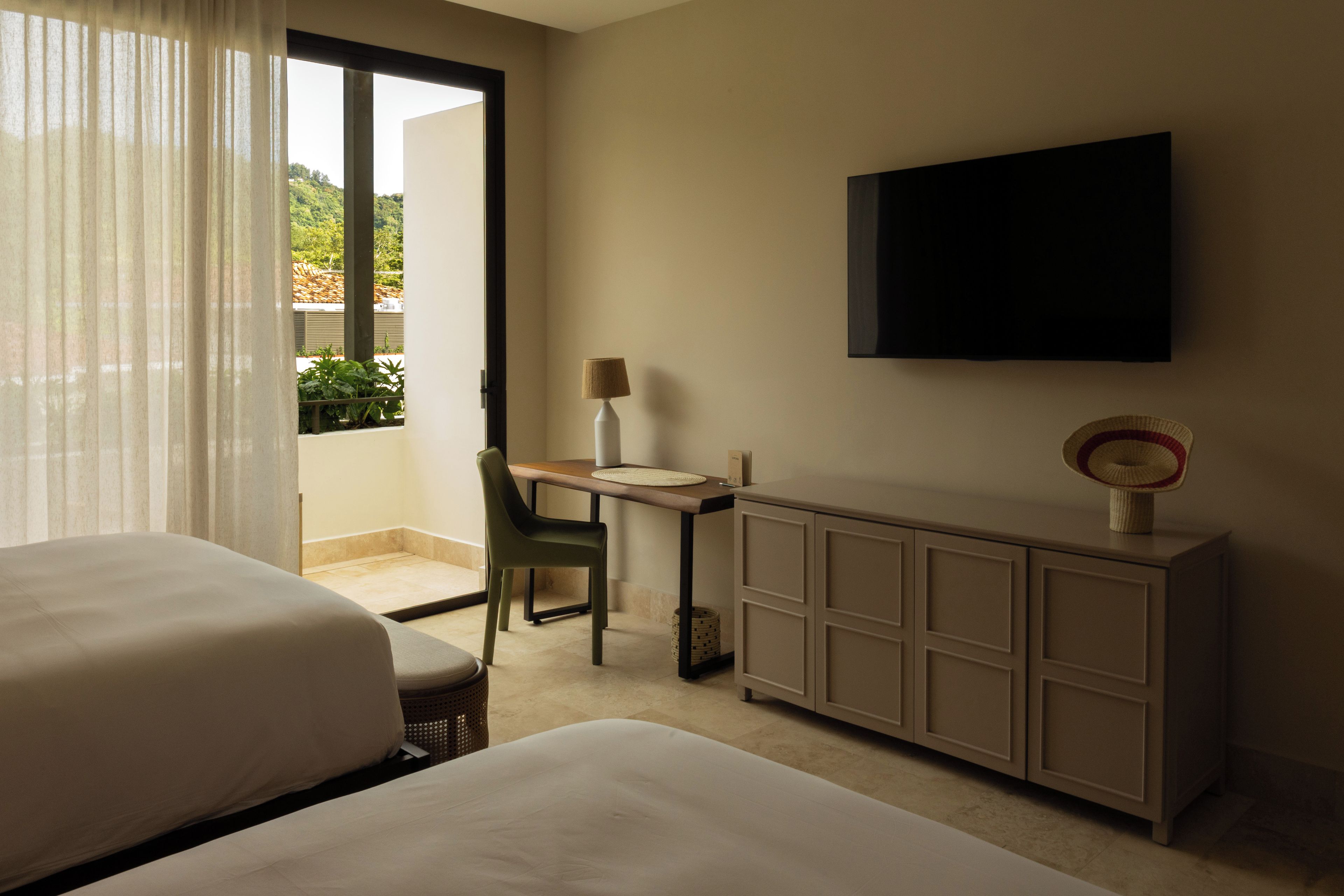 Habitación de hotel con dos camas, un escritorio, una silla, un televisor y un armario.