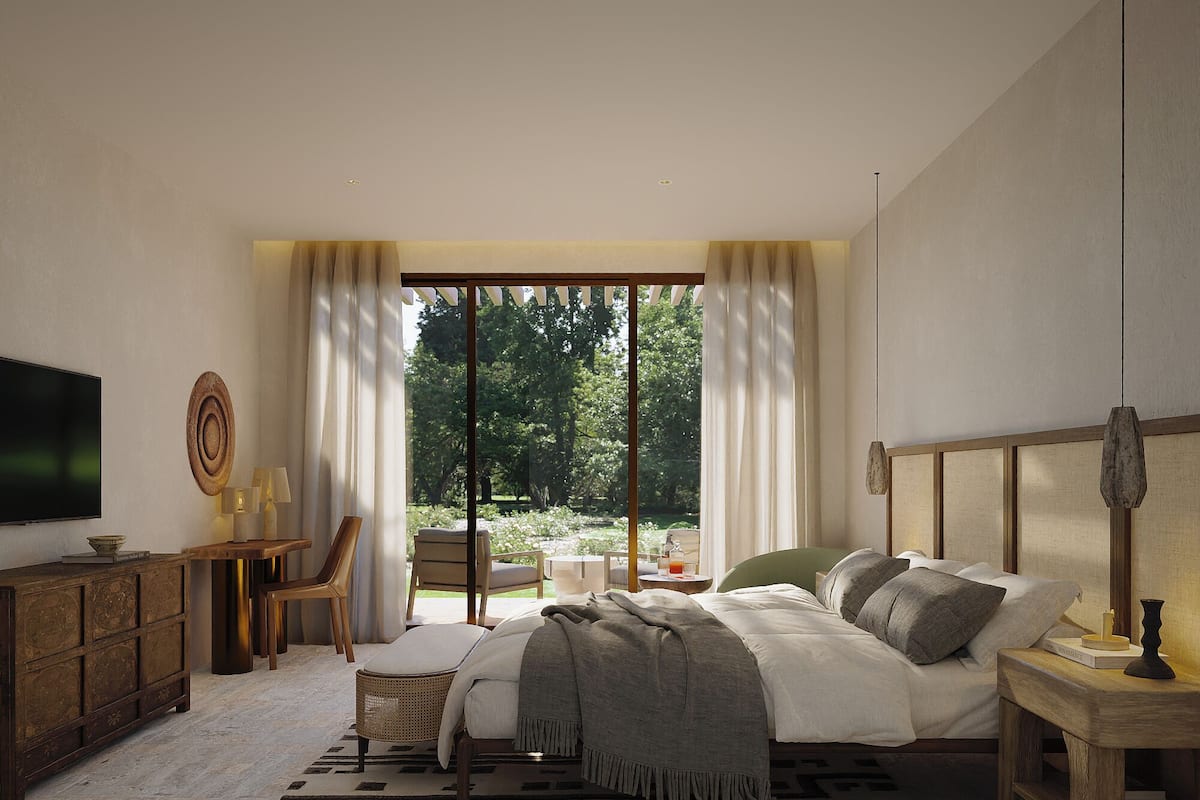 Un dormitorio con una cama grande, televisor, escritorio y vista a un jardín.