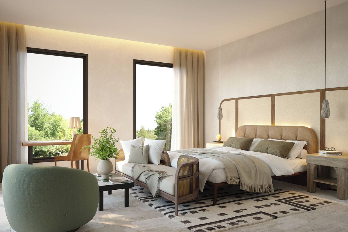 Un dormitorio moderno con una cama grande, un sillón verde, una mesita de noche con una lámpara y vistas a árboles a través de amplias ventanas.