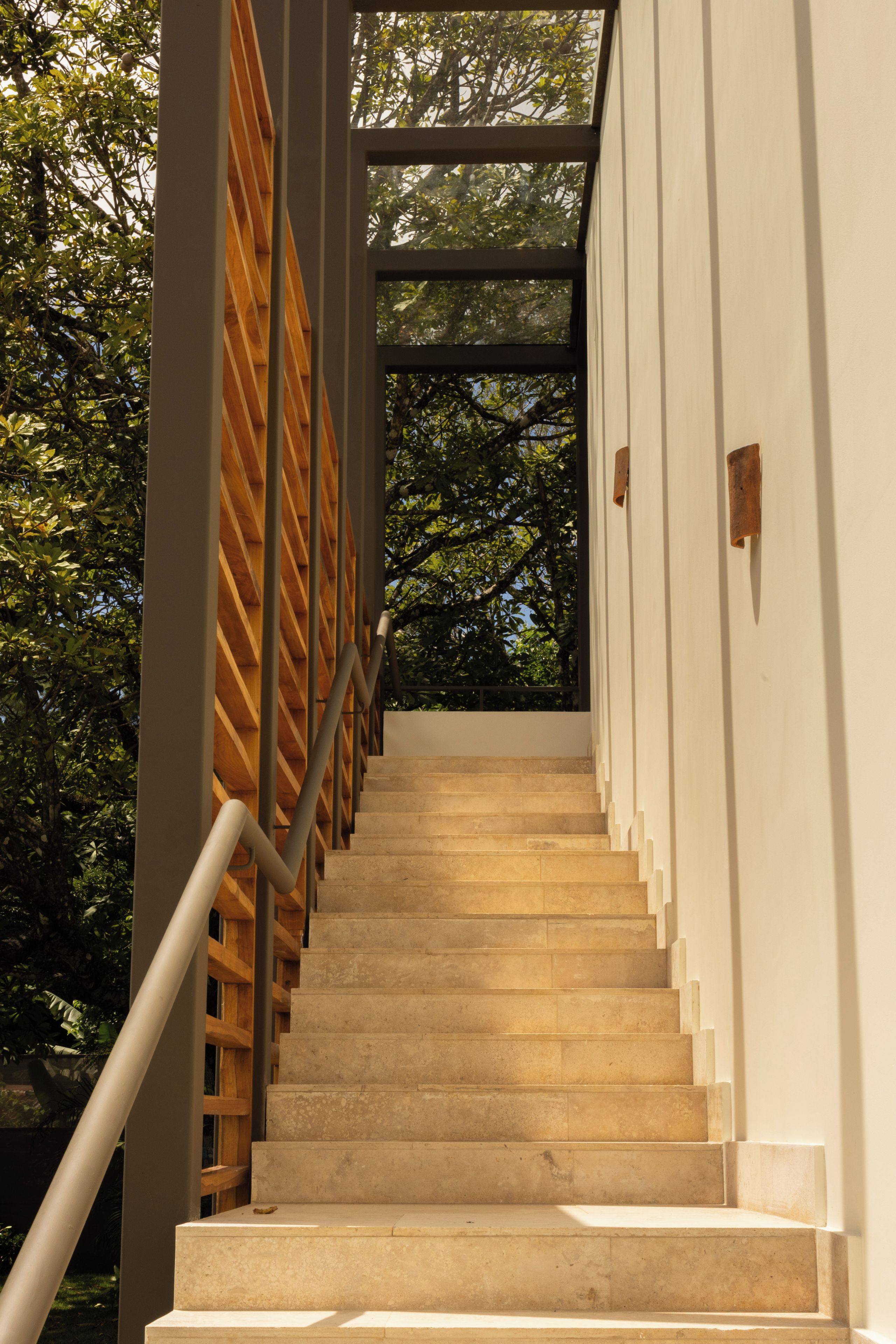 Una escalera con barandilla de madera y peldaños color beige que sube a un nivel superior.