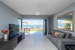 Una sala de estar moderna con un televisor de pantalla plana, un sofá y una mesa de comedor con sombrillas para el exterior.