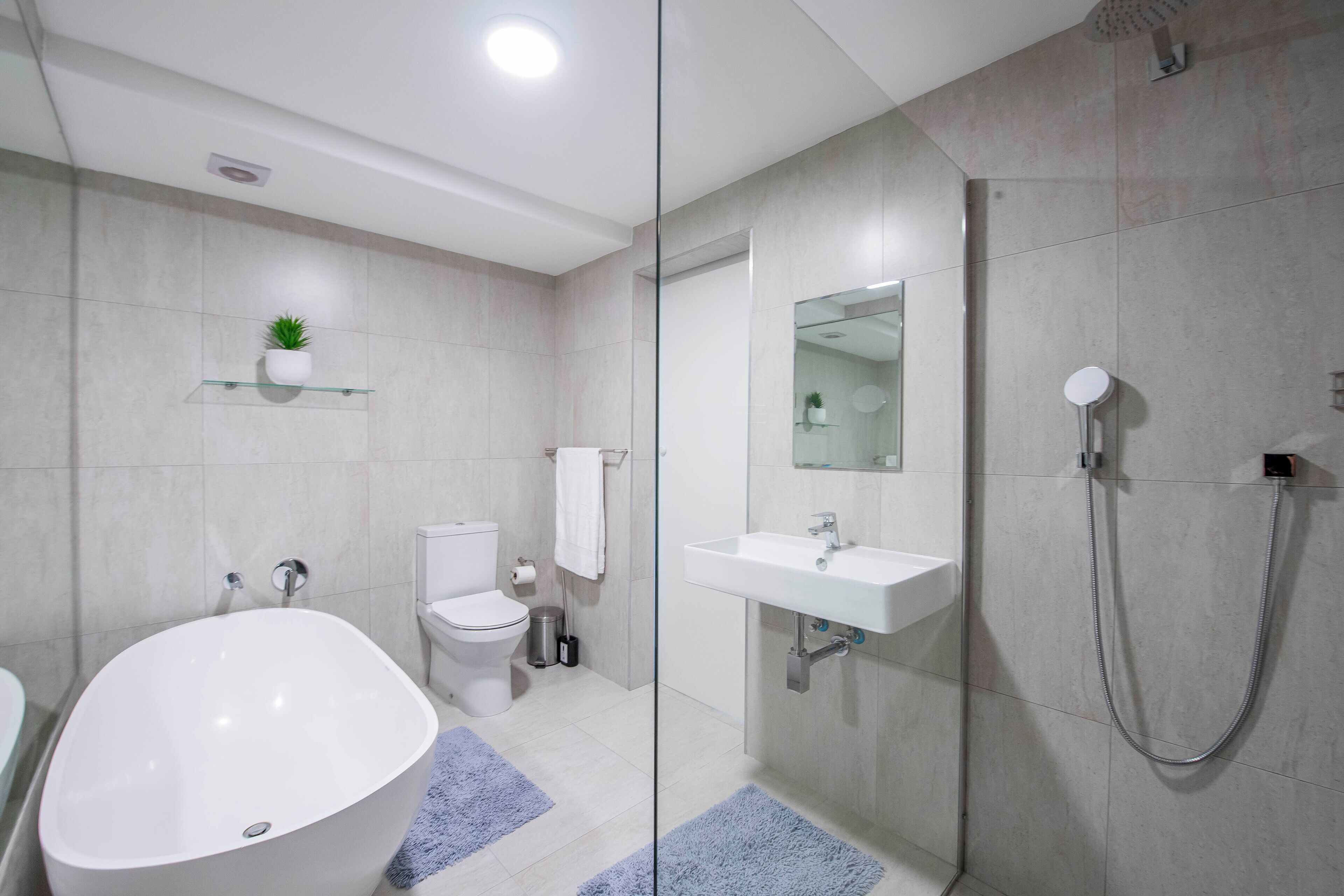 A modern bathroom with a freestanding bathtub, a toilet, a sink, and a glass-enclosed shower area.