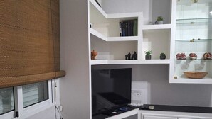 Moderni keittiö, jossa on valkoiset kaapit, musta työtaso ja sisäänrakennettu televisio.
