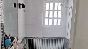Kylpyhuoneessa on valkoinen pesuallas, wc-istuin, kylpyamme ja ikkuna.