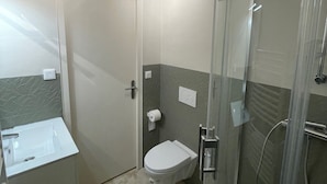 Une salle de bain équipée de toilettes, d’un lavabo et d’une douche à parois en verre.