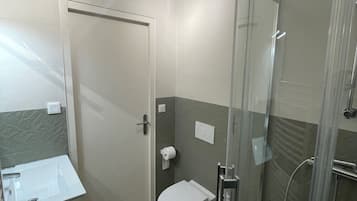 Een douche, handdoeken, zeep, toiletpapier
