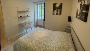 Une chambre à coucher comprenant un lit, une fenêtre, une étagère et un haut-parleur fixé au mur.