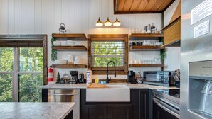 Een moderne keuken met houten planken, een roestvrijstalen koelkast en een raam met uitzicht op bomen.