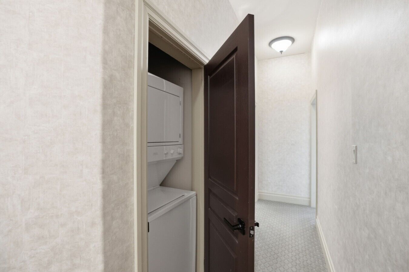 A hallway with a closed door, a closet with hanging space, and a light fixture on the ceiling.