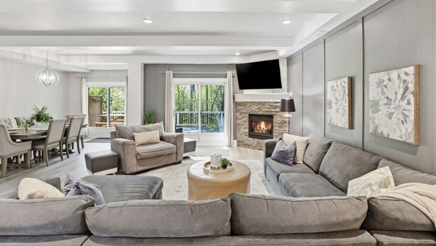 A modern living room with a fireplace, a dining area, and a large window.