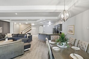 A modern living room with a sofa, dining table, and kitchen area.