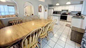 Una cocina amplia con armarios blancos, una mesa de comedor de madera y un ventilador de techo.