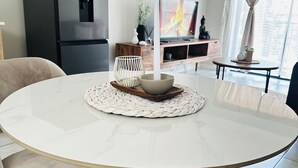 Moderni keittiö, jossa on musta jä äkaappi, ruokapöytä tuoleineen ja televisio, jolta näkyy kohtaus tulipalosta.