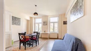 A cozy room with a sofa, a dining table with chairs, and a window providing natural light. - Sunny Boutique Studio, 57 m², Art Nouveau hotel, ideal for extended stays (Wien)