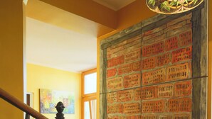 A staircase with ornate black railings, a large stained glass light fixture, and a wall with a grid of red and orange tiles. - Sunny Boutique Studio, 57 m², Art Nouveau hotel, ideal for extended stays (Wien)