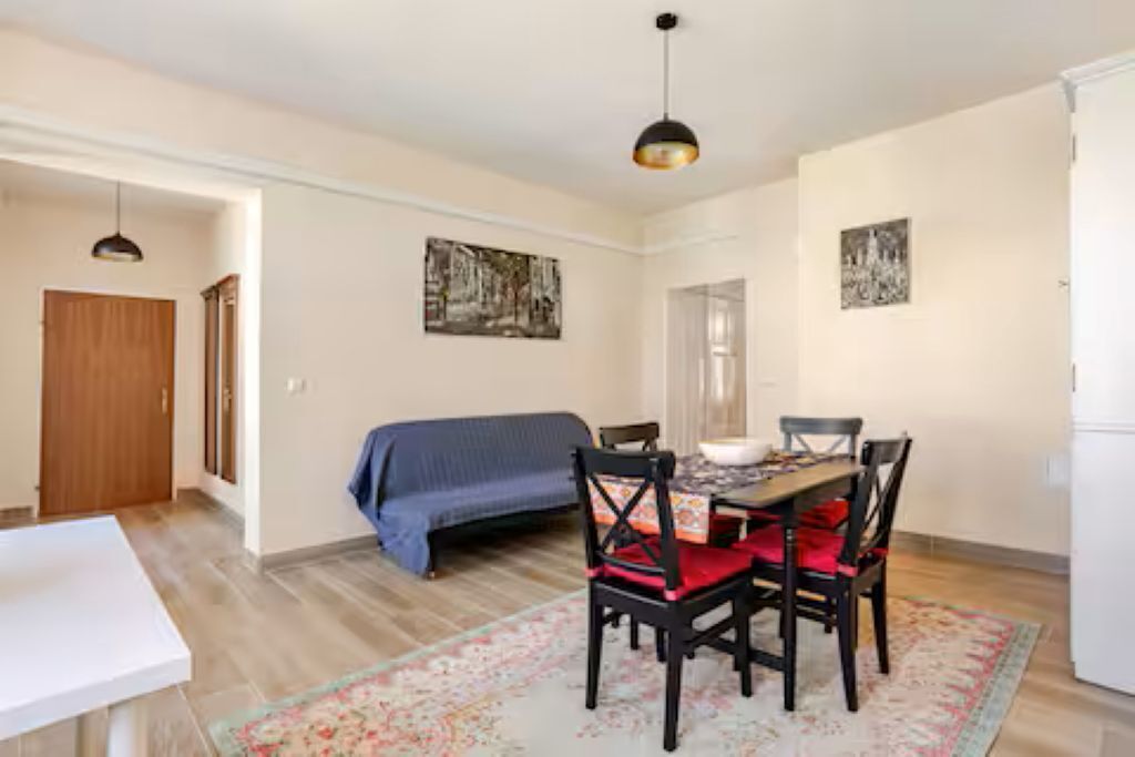 A dining area with a table set for four, a sofa, and a ceiling light.