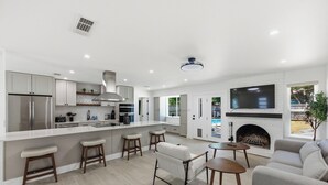 A modern kitchen with a large island, bar stools, and a built-in oven. - Austin Escape: Stylish 3BR/4 Beds + Private Pool (Austin)