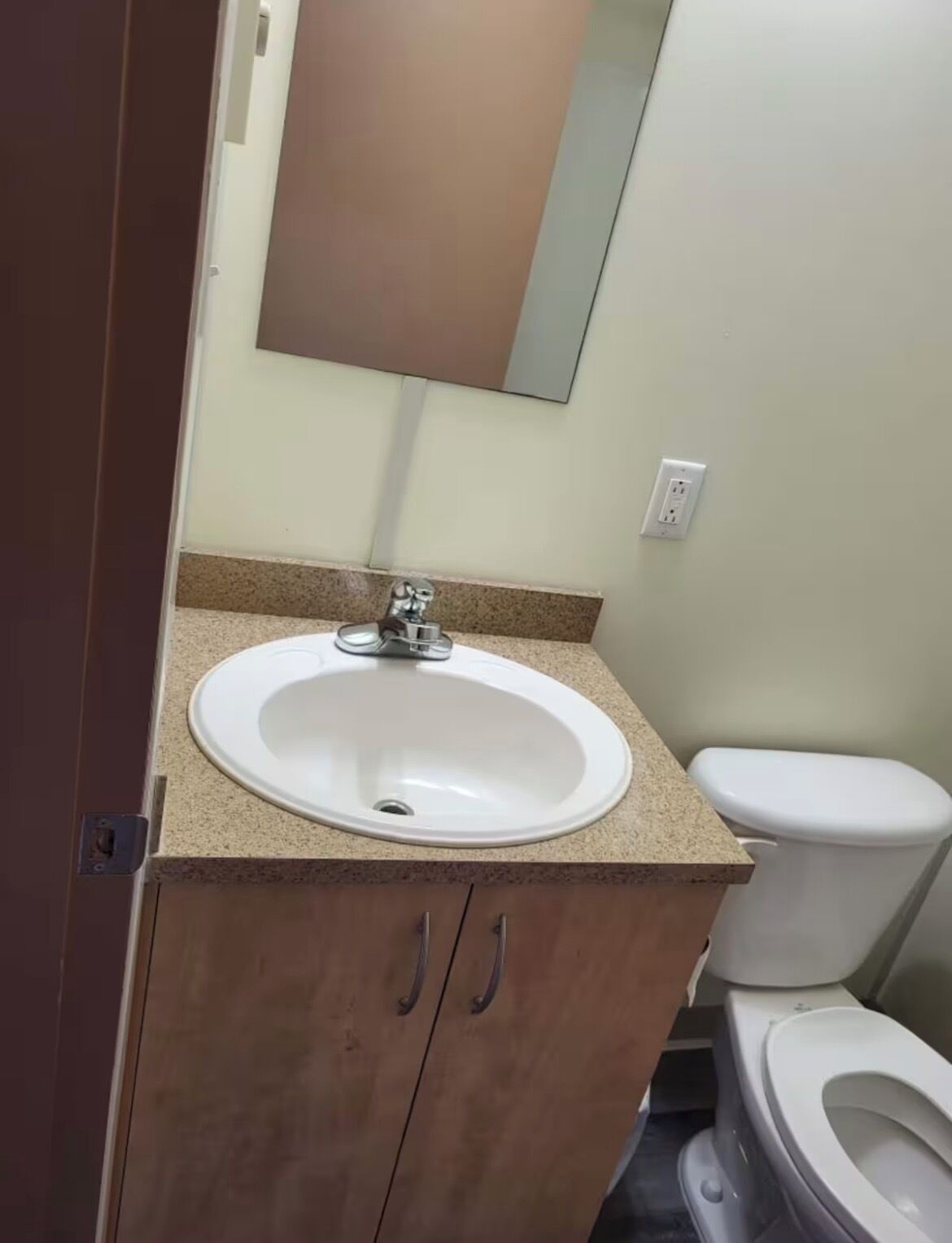 Un bagno con un lavandino bianco, uno specchio sopra e un water.