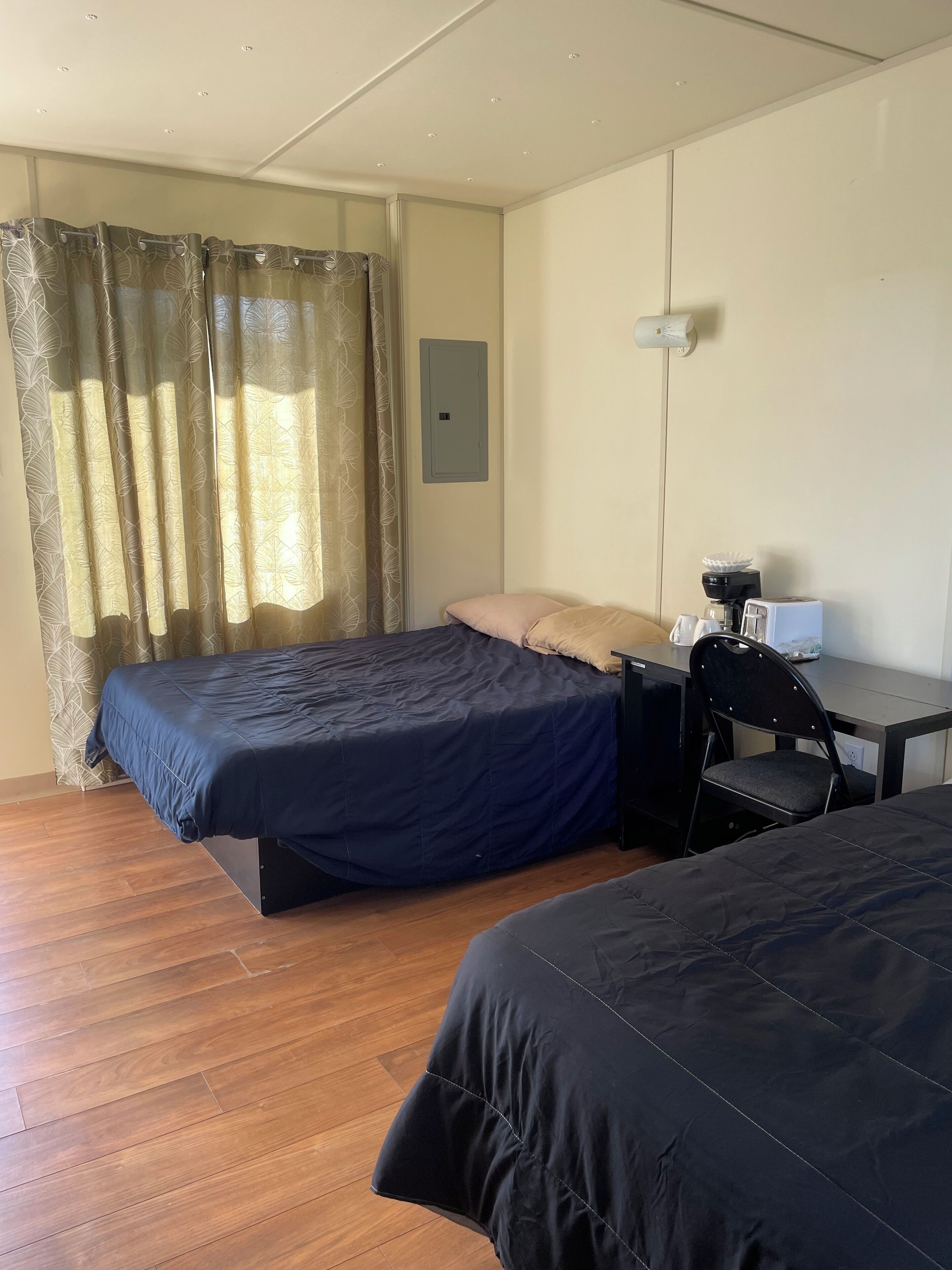 Una habitación de hotel con cama, escritorio, silla y cafetera.