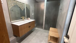 Une salle de bain moderne avec un meuble-lavabo en bois, un grand miroir et un espace douche.