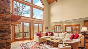 A spacious living room with a large sectional sofa, a coffee table, and a stone fireplace.