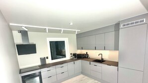 A modern kitchen with grey cabinets, a built-in oven, a microwave, and a sink.