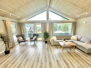 Un salon spacieux avec un plafond haut, de grandes fenêtres et une vue sur un balcon.