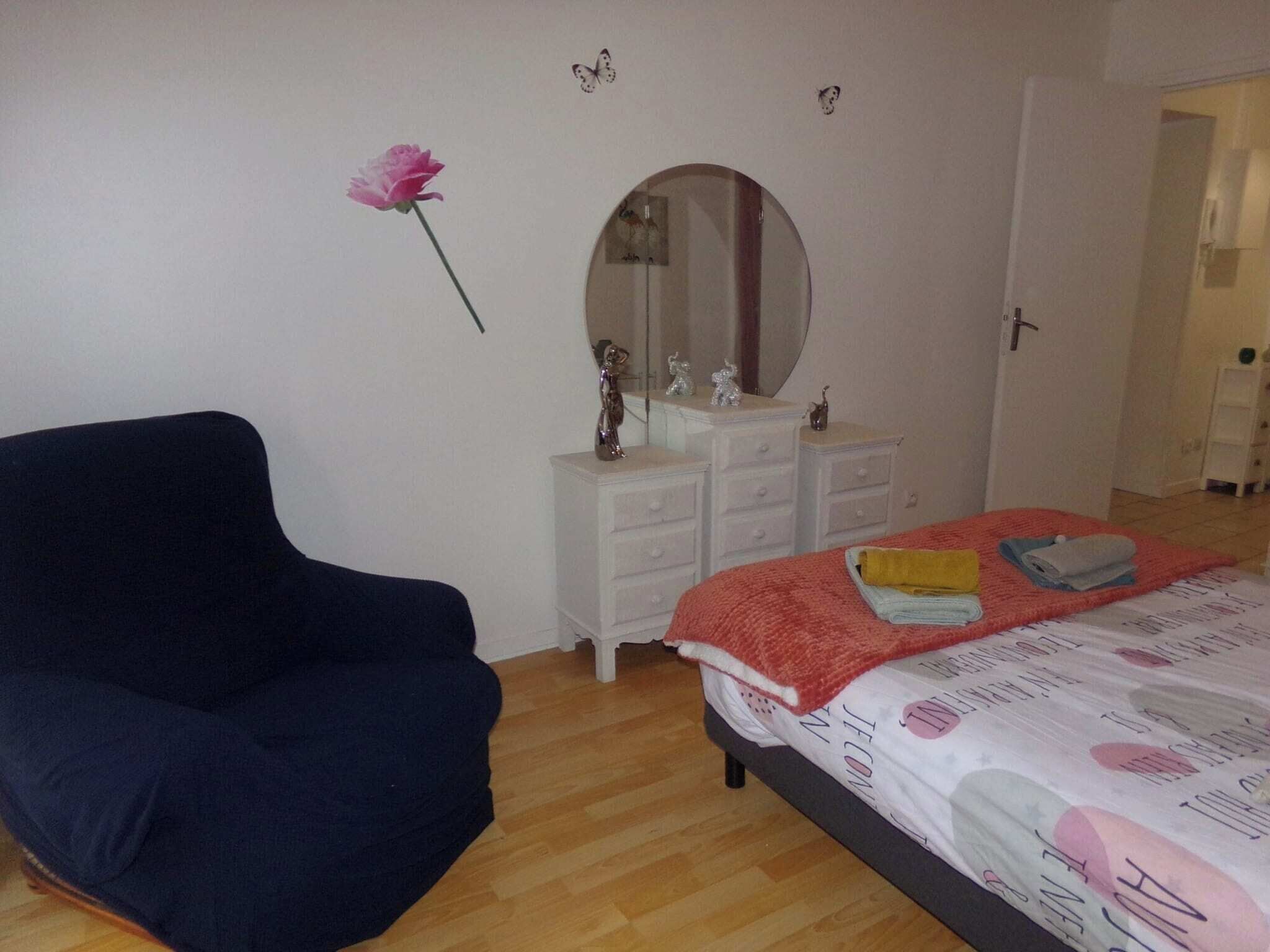 A bedroom with a bed, a dresser, a mirror, a chair, and a wall decoration.