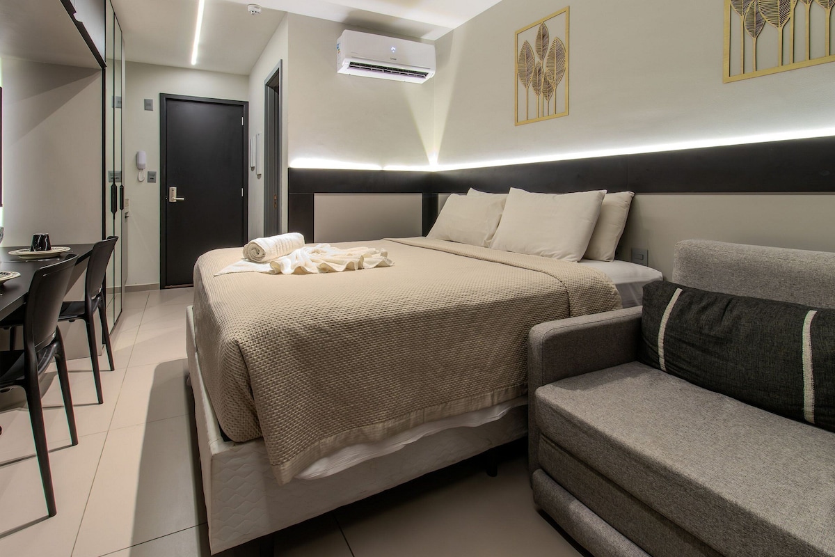A modern hotel room with a bed, a sofa, a desk, and a chair.
