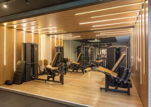 A gym with exercise equipment, wooden walls, and a mirrored wall. - Beach Haus  (João Pessoa)