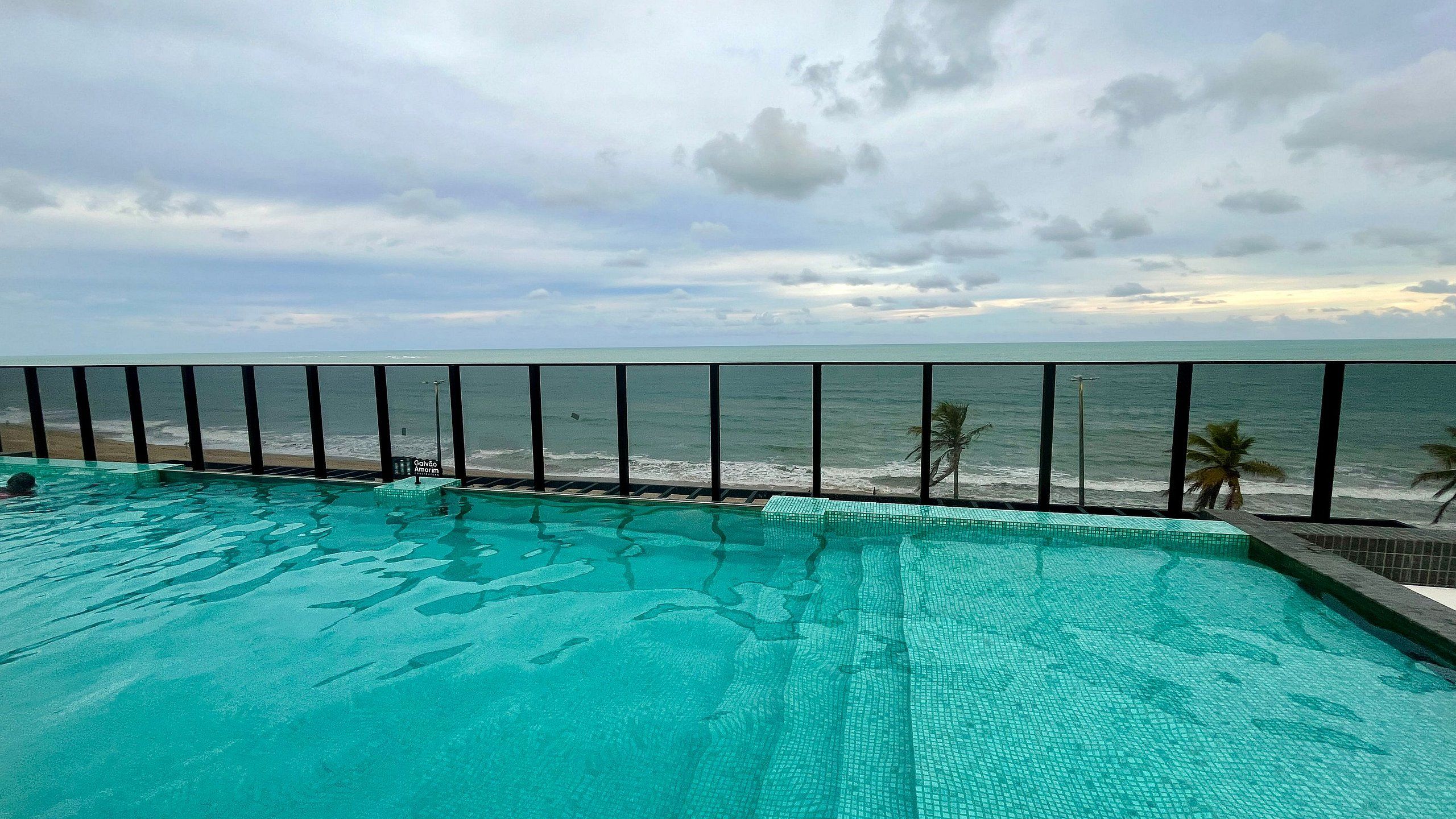 A swimming pool with a view of the ocean and beach.