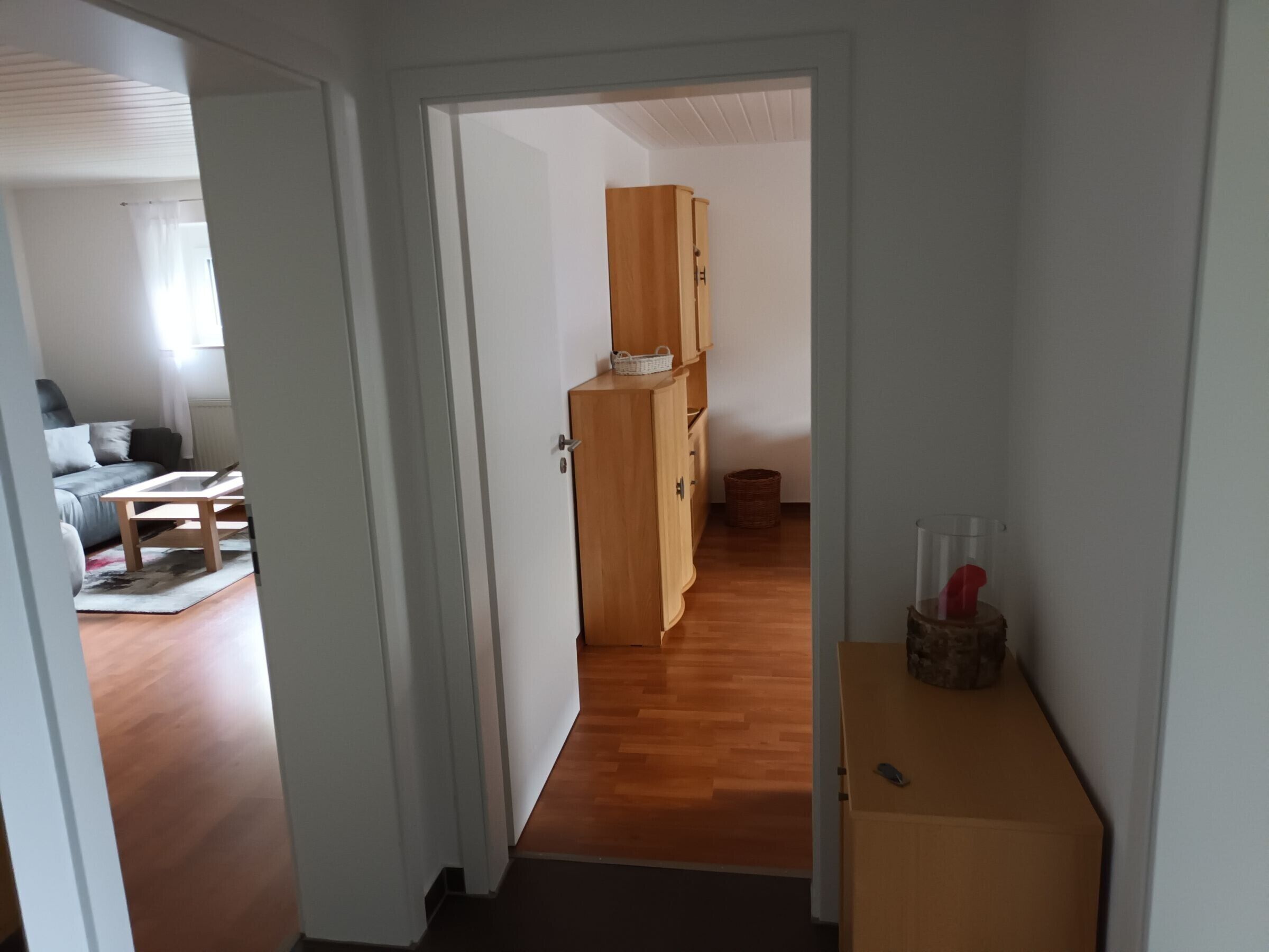 Un couloir avec un meuble en bois, un panier et une petite table sur laquelle se trouvent divers objets.