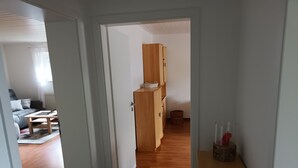 A hallway with a wooden cabinet, a basket, and a small table with items on it. - Holiday Apartment Doris, 57sqm, 1 Living-/Bedroom, max 2 People (Sinsheim)