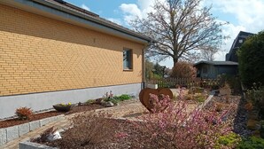 A brick house with a garden featuring a heart-shaped planter and various plants. - Holiday Apartment Doris, 57sqm, 1 Living-/Bedroom, max 2 People (Sinsheim)