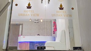 A hotel entrance with glass doors, a reception desk, and a staircase leading up. - Hotel Urban View (Ahmedabad)
