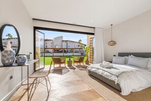 Camera d'albergo moderna con un letto grande, una scrivania con uno specchio e vista su un edificio e del verde.
