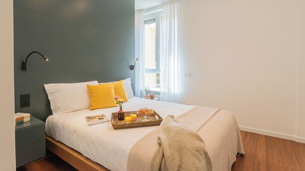 A modern bedroom with a bed, bedside table, and a window with curtains. - Como Volta Square with Terrace (Como)