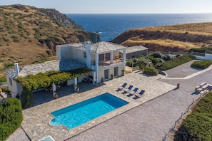 Una casa moderna con piscina, zona de estar exterior y vista al mar.