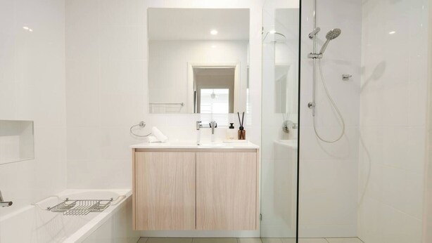 Une salle de bain moderne avec une douche à parois de verre, un meuble-lavabo en bois et une baignoire.