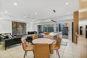 Una cocina moderna con comedor, que cuenta con una mesa de mármol y sillas de cuero.