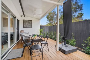 Un patio al aire libre con una mesa de madera, sillas, un sofá y un ventilador de techo.