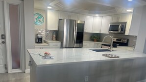 Una cocina moderna con armarios blancos, electrodomésticos de acero inoxidable y una isla central.