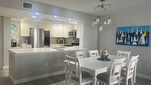 Una cocina moderna con armarios blancos, electrodomésticos de acero inoxidable y una isla central.
